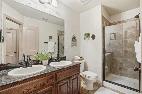 a bathroom with a double vanity sink toilet mirror and shower