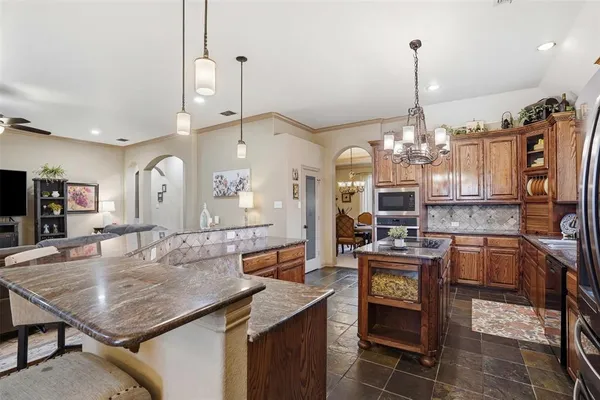 a kitchen with stainless steel appliances kitchen island granite countertop a table chairs in it and wooden floors