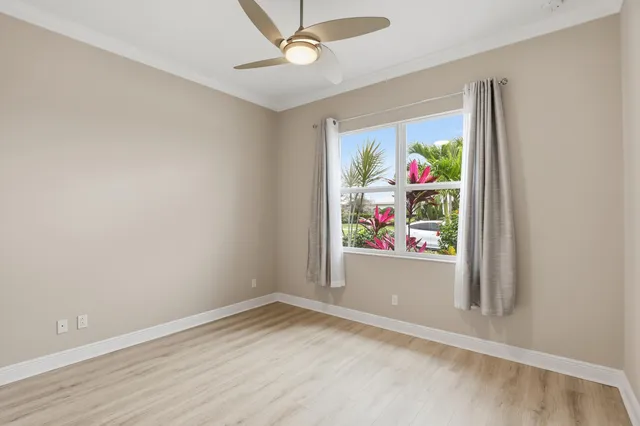 an empty room with window ceiling fan and wooden floor