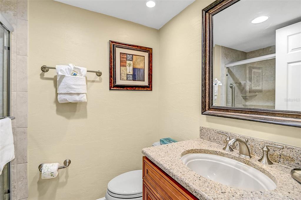 6518 Midnight Pass Road, Unit 407 Sarasota, FL 34242 - Photo 15 of 48 a bathroom with a granite countertop toilet sink and mirror