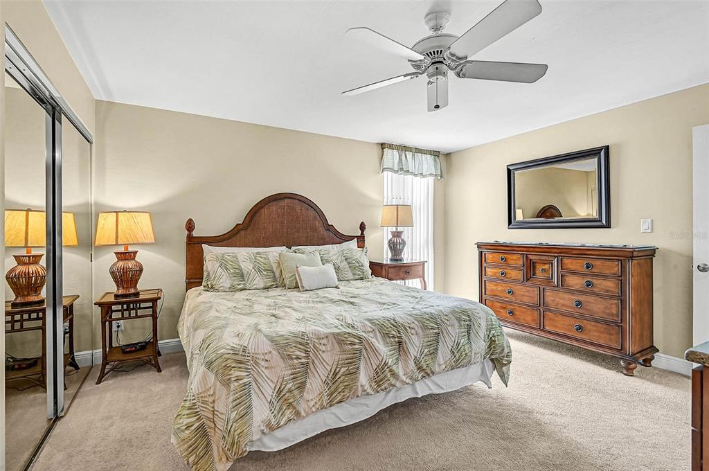 6518 Midnight Pass Road, Unit 407 Sarasota, FL 34242 - Photo 20 of 48 a bedroom with a bed a chandelier and dresser