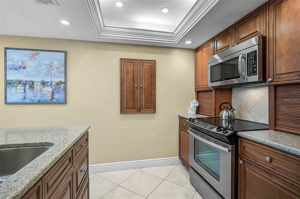 6518 Midnight Pass Road, Unit 407 Sarasota, FL 34242 - Photo 26 of 48 a kitchen with stainless steel appliances granite countertop a stove a microwave and a sink
