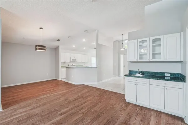 an empty room with wooden floor ceiling fan and windows