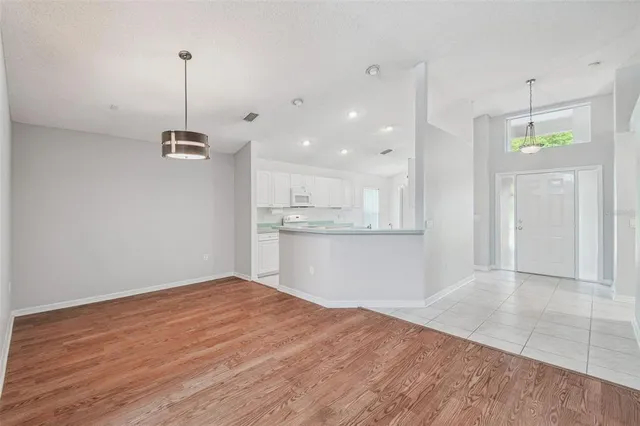a view of an empty room with wooden floor and a ceiling fan