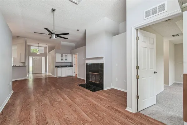 an empty room with chandelier fan and windows