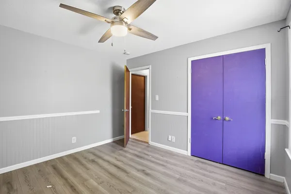 an empty room with closet and a ceiling fan