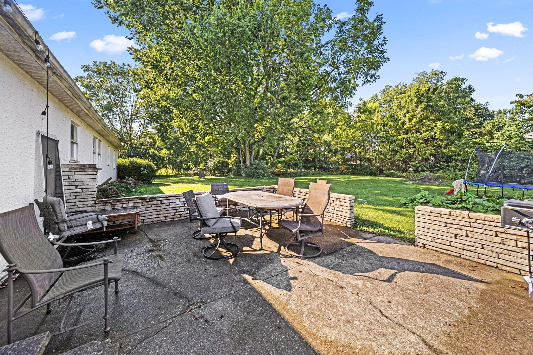 6344 Post Road Dublin, OH 43017 - Photo 29 of 45 Expansive concrete patio with stone-faced retaining walls and a lush green lawn