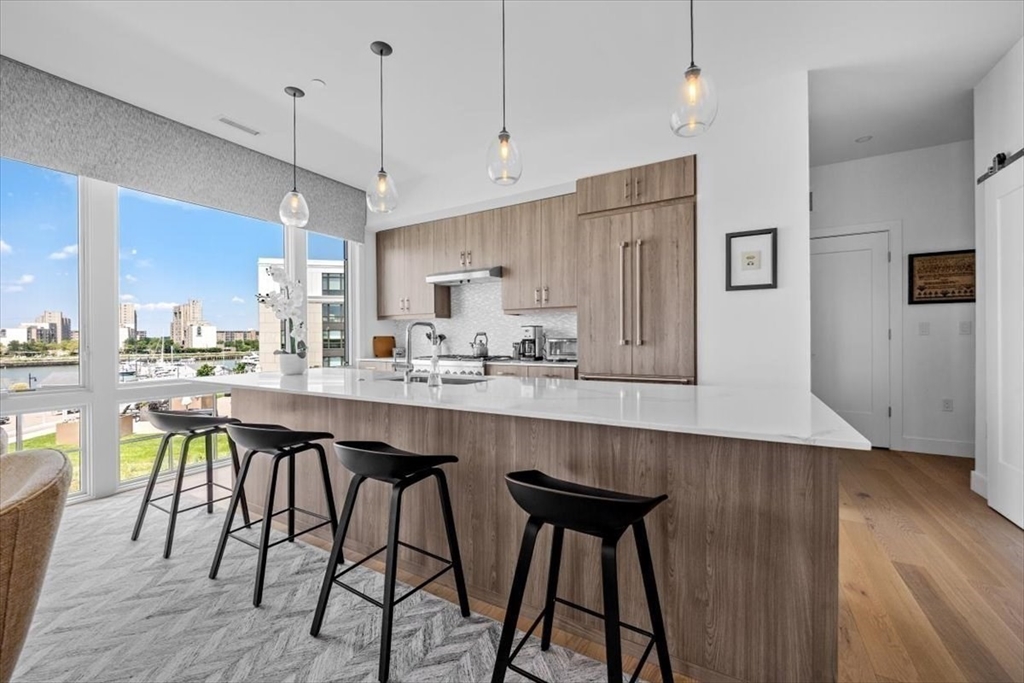 10 Shipyard Drive, Unit 312 Hingham, MA 02043 - Photo 16 of 32 a kitchen with stainless steel appliances granite countertop a sink a stove a refrigerator and island with wooden floor