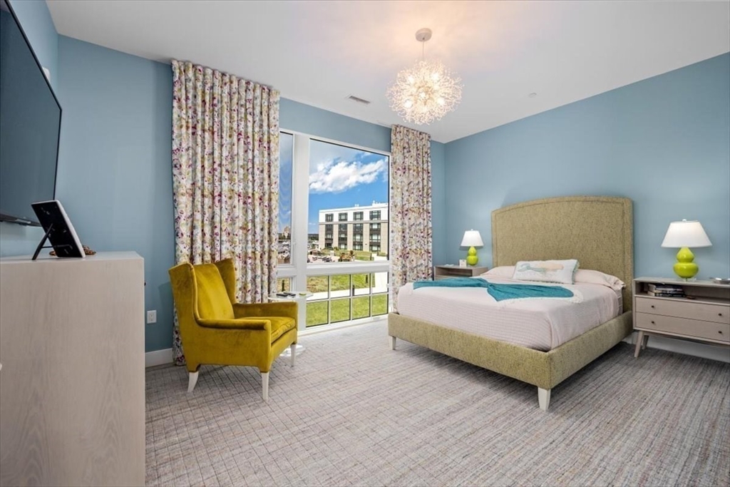 10 Shipyard Drive, Unit 312 Hingham, MA 02043 - Photo 18 of 32 a bedroom with a bed and a chandelier