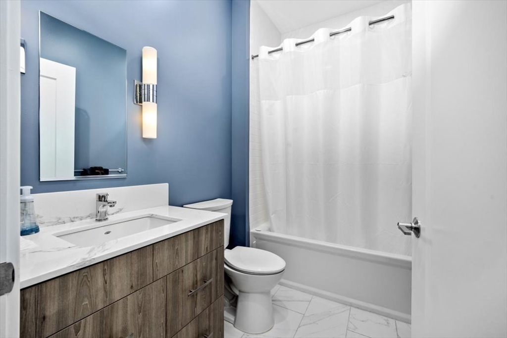 10 Shipyard Drive, Unit 312 Hingham, MA 02043 - Photo 24 of 32 a bathroom with a sink a toilet and shower curtain