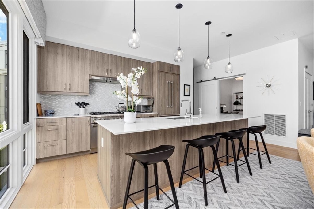 10 Shipyard Drive, Unit 312 Hingham, MA 02043 - Photo 7 of 32 a kitchen with stainless steel appliances granite countertop a table chairs stove and white cabinets