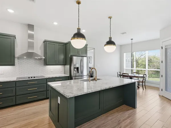 a kitchen with kitchen island granite countertop a sink and a refrigerator