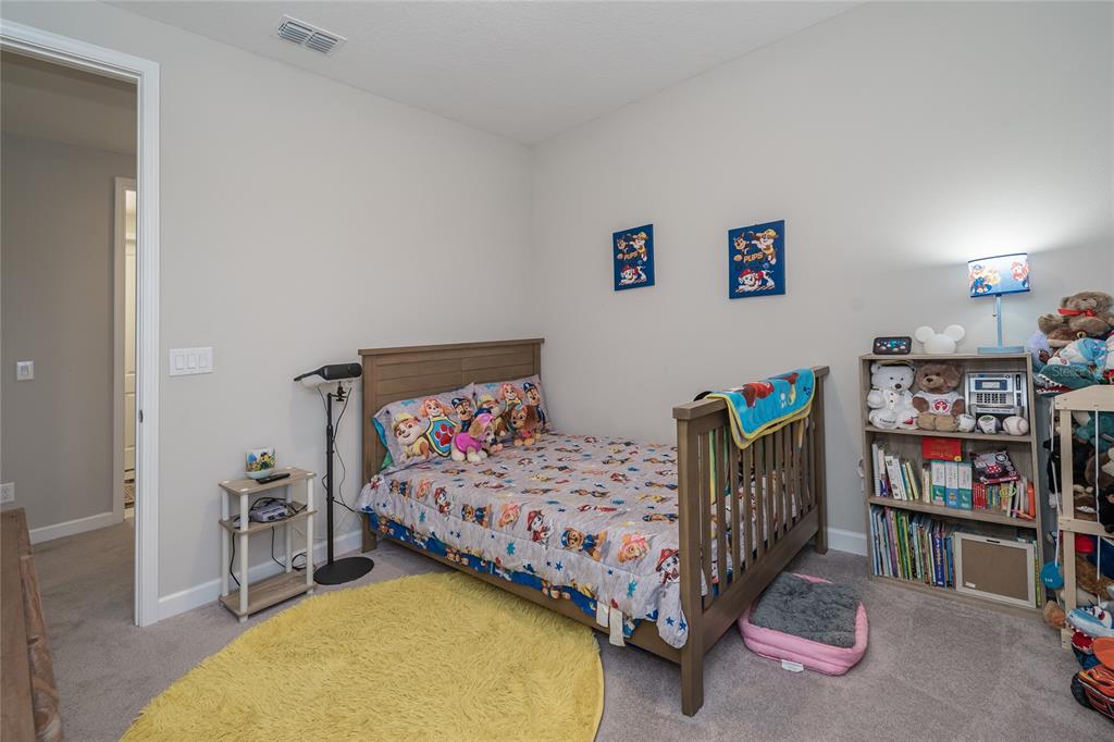 8099 Lago Mist Way Wesley Chapel, FL 33545 - Photo 33 of 56 a bedroom with a bed and a book shelf