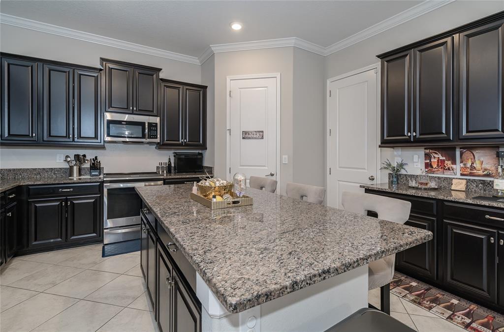 8099 Lago Mist Way Wesley Chapel, FL 33545 - Photo 7 of 56 a kitchen with granite countertop a sink a stove and a wooden cabinets