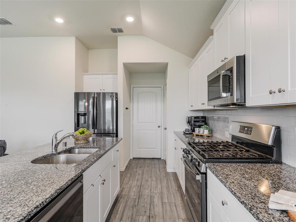 4517 Ashmark Road Aubrey, TX 76227 - Photo 21 of 26 a kitchen with stainless steel appliances granite countertop a sink stove and cabinets