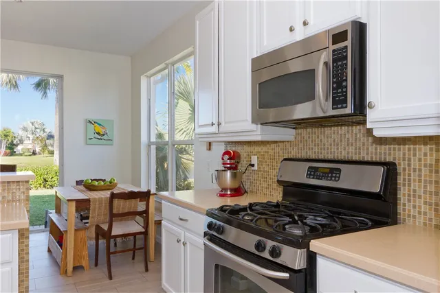 a kitchen with stainless steel appliances a stove a microwave and white cabinets