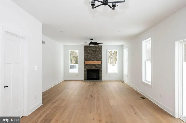 an empty room with wooden floor fireplace and windows
