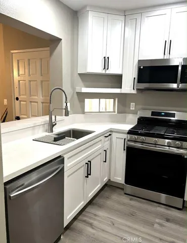 a kitchen with stainless steel appliances white cabinets a sink and a stove