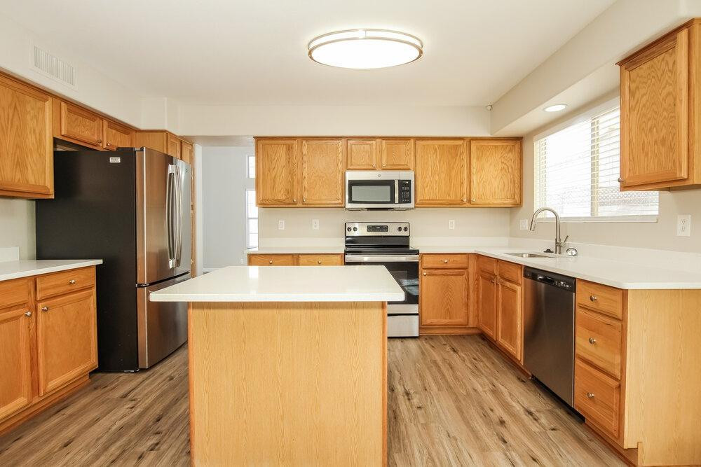 9243 West St John Road Peoria, AZ 85382 - Photo 10 of 17 a kitchen with a refrigerator a stove top oven a sink dishwasher and wooden cabinets with wooden floor