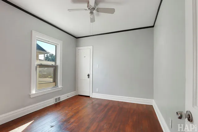 an empty room with wooden floor fan and windows