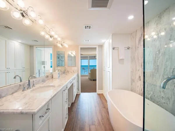 a spacious bathroom with a granite countertop tub sink shower and mirror