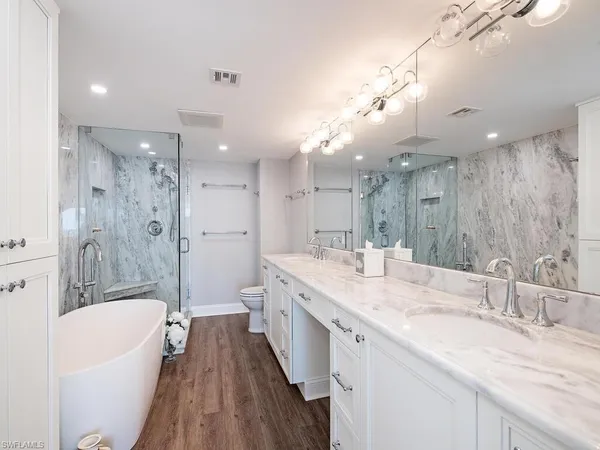 a bathroom with a granite countertop double vanity sink a mirror and a bathtub
