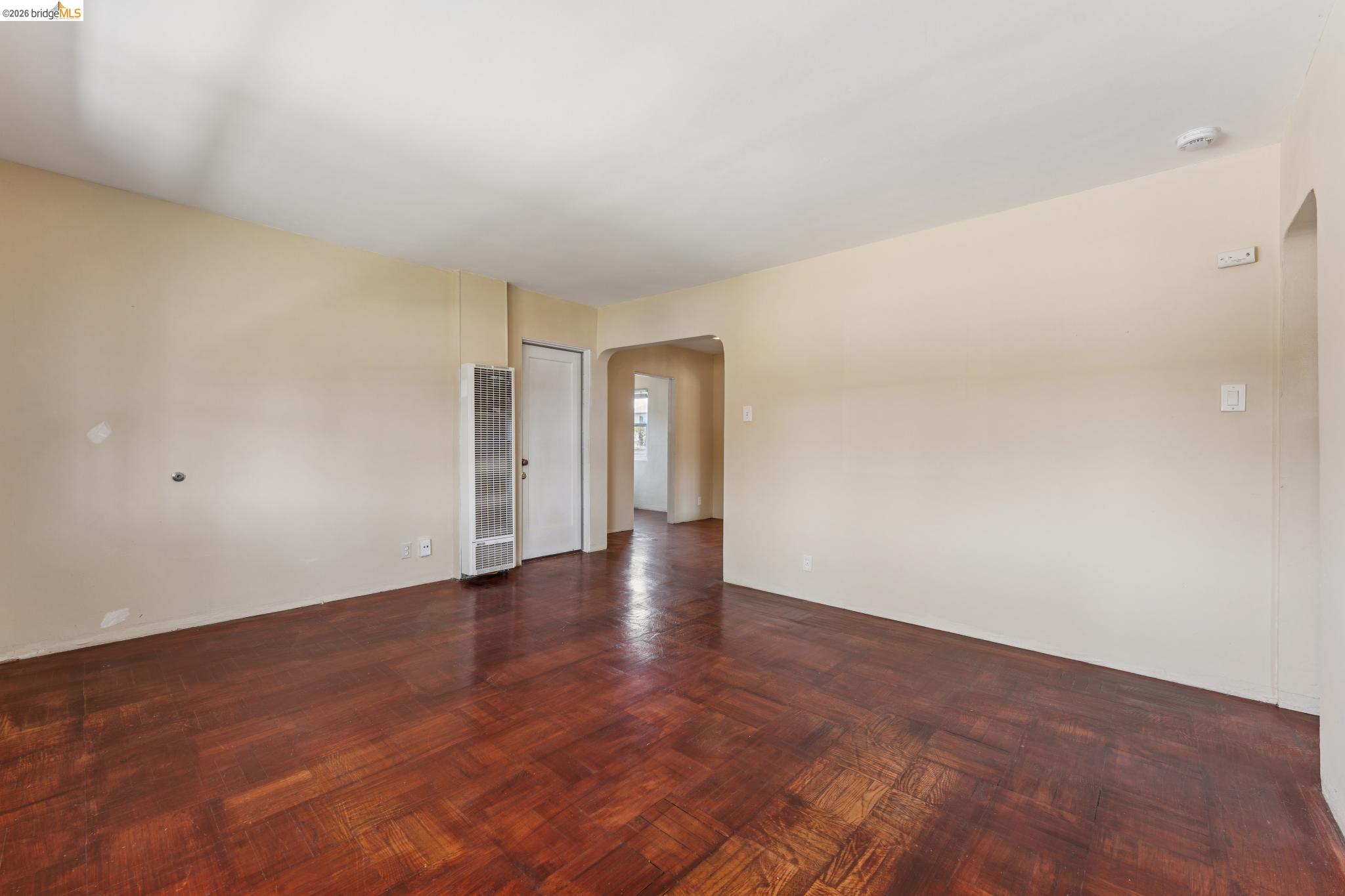 2879 Rheem Avenue Richmond, CA 94804 - Photo 9 of 45 Spacious room featuring wood-finish parquet flooring, light-toned walls, and a wall-mounted heater