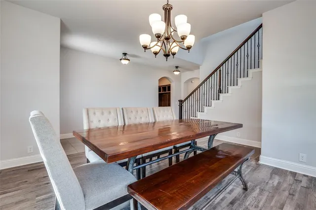 a dining room with wooden floor a chandelier a wooden table and chairs