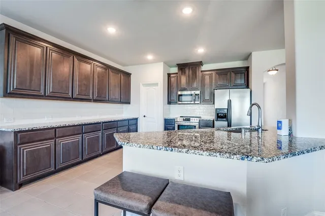 a kitchen with kitchen island granite countertop wooden cabinets a sink and dishwasher