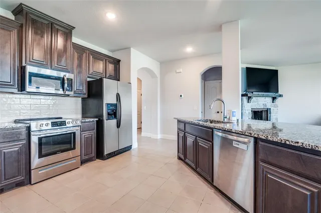 a kitchen with stainless steel appliances granite countertop a stove top oven a sink and a refrigerator