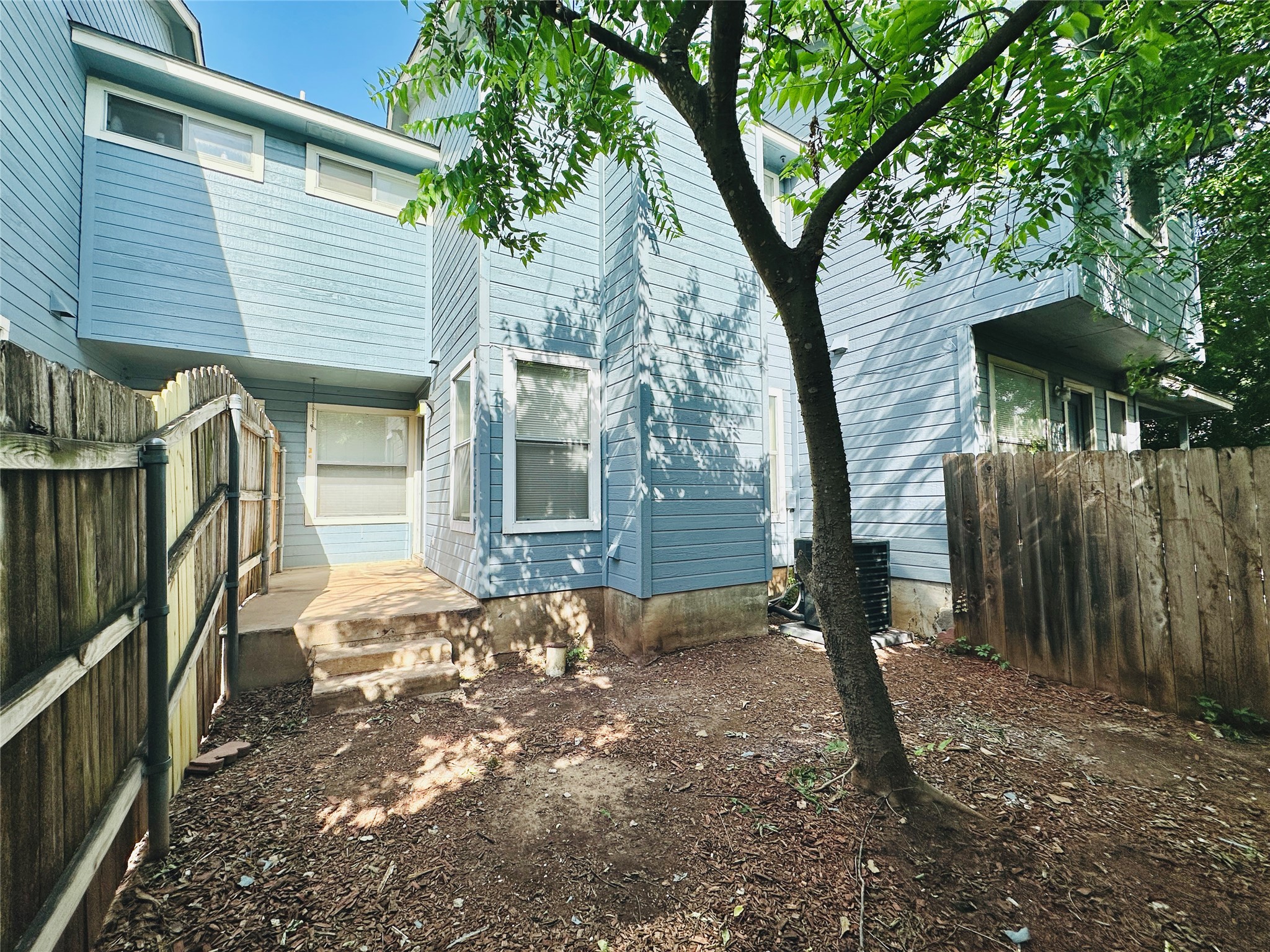 8814 Schick Road, Unit C Austin, TX 78729 - Photo 35 of 35 A private yard with a wooden fence and mature trees offers a tranquil outdoor escape.