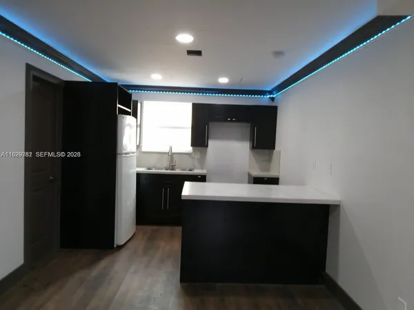 a view of kitchen with stainless steel appliances a sink and wooden floor