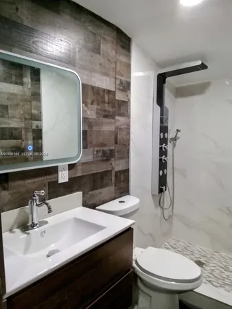a bathroom with a sink a toilet a mirror and shower