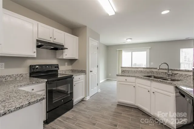 a kitchen with granite countertop a stove sink and cabinets