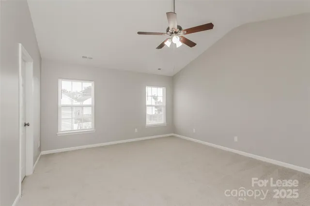 an empty room with chandelier fan and windows