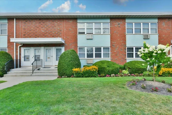 a view of a house with brick walls and a yard with plants