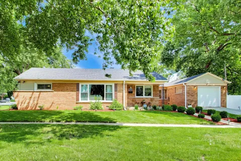 a front view of a house with a garden and trees
