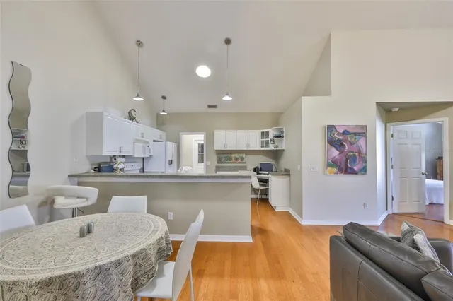 a living room with stainless steel appliances furniture a rug and a kitchen view