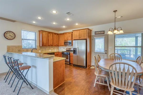 a kitchen with granite countertop a table chairs stove and refrigerator