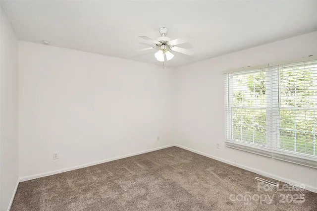 an empty room with a window and a fan