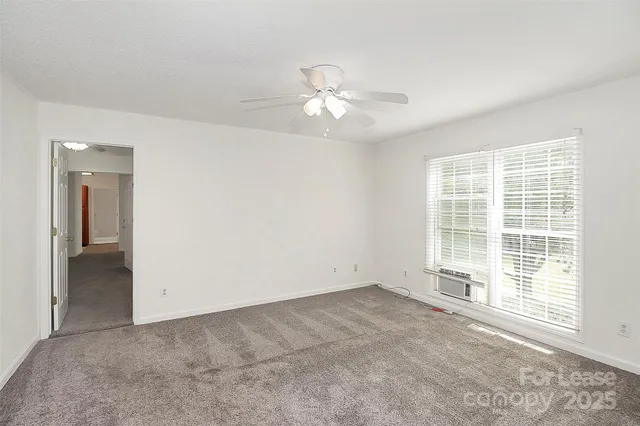 an empty room with chandelier fan and windows