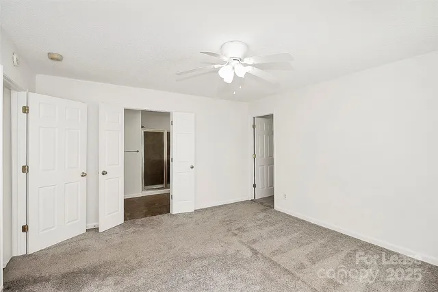 a view of an empty room and chandelier fan