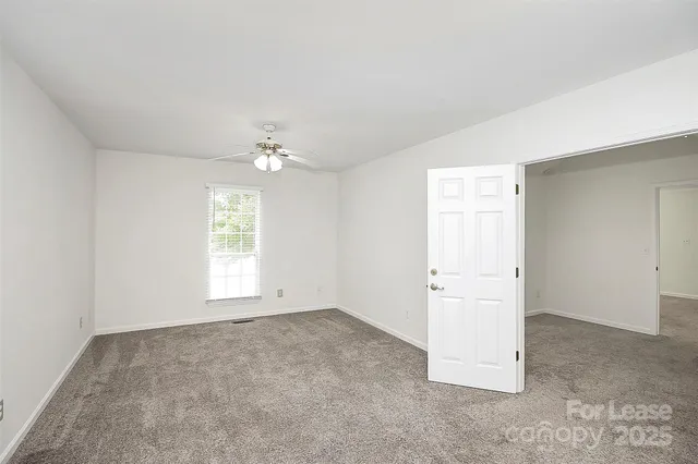 an empty room with windows and chandelier fan