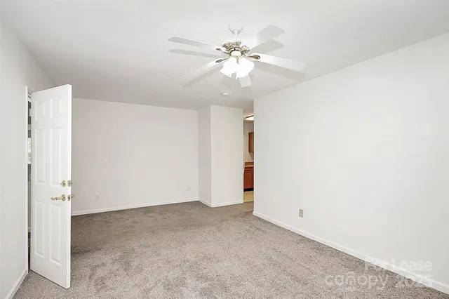 an empty room with a chandelier fan and closet area