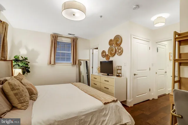 a bedroom with a bed and a flat tv screen on dresser