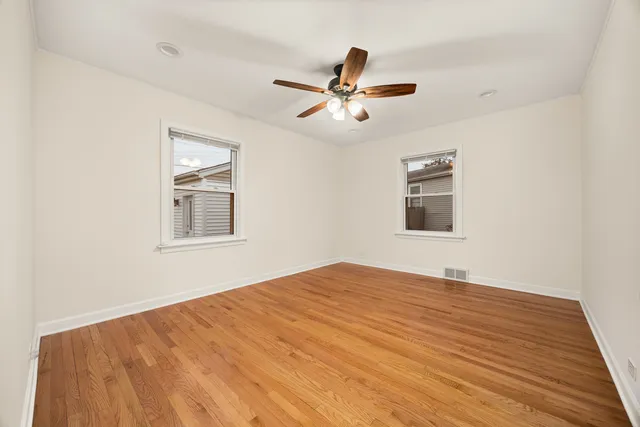 a view of a big room with wooden floor and windows
