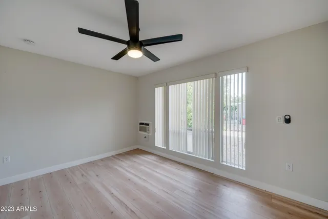 a view of empty room with wooden floor and fan