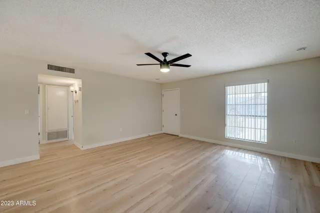 an empty room with wooden floor and ceiling fan