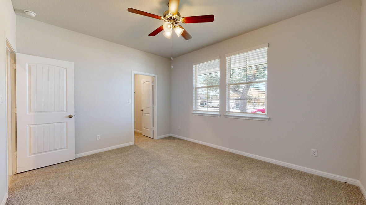 808 Gauge Road Thorndale, TX 76577 - Photo 19 of 31 A comfortable bedroom with soft carpeting features a ceiling fan and abundant natural light from multiple windows.