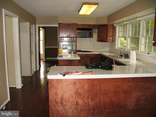 1600 Golf Course Drive Bowie, MD 20721 - Photo 6 of 21 a living room with stainless steel appliances kitchen island granite countertop a refrigerator a stove a sink and a dining table with wooden floor